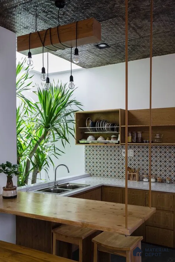 A kitchen with marble counter tops and wooden cabinetry, along with an island in the middle of the middle of the island with stairs leading to shop & more counter top space to an island in the middle of